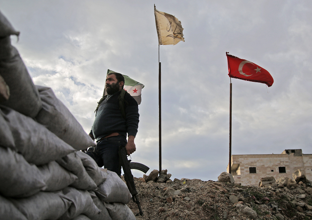 a fighter from faylaq al sham sham or levant legion one of the factions of the turkish backed national liberation front nlf factions is seen holding a kalashnikov assault rifle as he stands in front of the flags of l to r the syrian opposition the faction and turkey at a position in the village of kiridiyah about 30 kilometres west of the northern town of manbij on january 15 2019 photo afp a fighter from faylaq al sham sham or levant legion one of the factions of the turkish backed national liberation front nlf factions is seen holding a kalashnikov assault rifle as he stands in front of the flags of l to r the syrian opposition the faction and turkey at a position in the village of kiridiyah about 30 kilometres west of the northern town of manbij on january 15 2019 photo afp