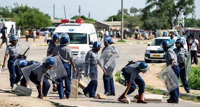 police officers make way for an ambulance by removing stones from a barricade during a stay away demonstration against the doubling of fuel prices on january 14 2019 in emakhandeni township bulawayo photo afp police officers make way for an ambulance by removing stones from a barricade during a stay away demonstration against the doubling of fuel prices on january 14 2019 in emakhandeni township bulawayo photo afp