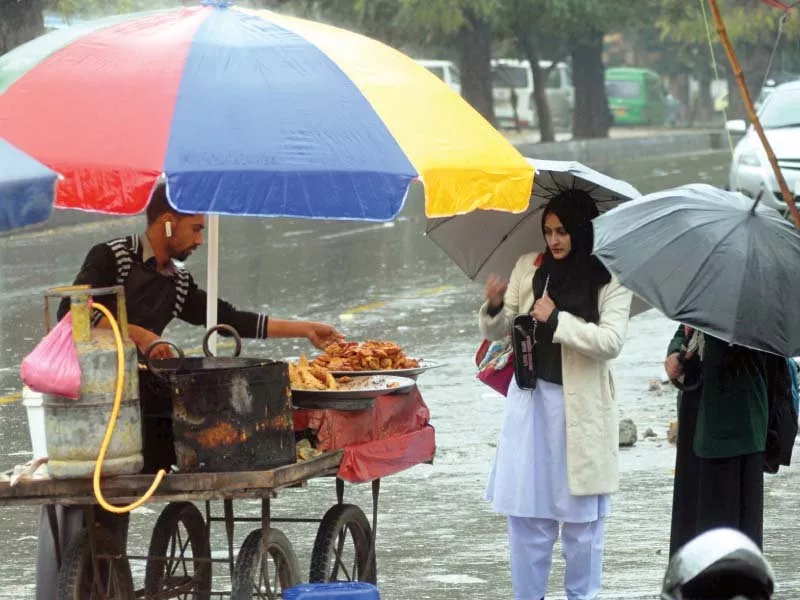women buy fritters pakoras from a roadside vendor in the capital while a road is flooded with rainwater as heavy rains lashed the twin cities photo zafar aslam express women buy fritters pakoras from a roadside vendor in the capital while a road is flooded with rainwater as heavy rains lashed the twin cities photo zafar aslam express