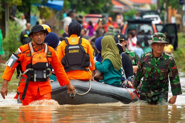 indonesian rescuers evacuate residents from their homes in makassar on jan 24 2019 as heavy rain and strong winds pounded the southern part of sulawesi island photo afp