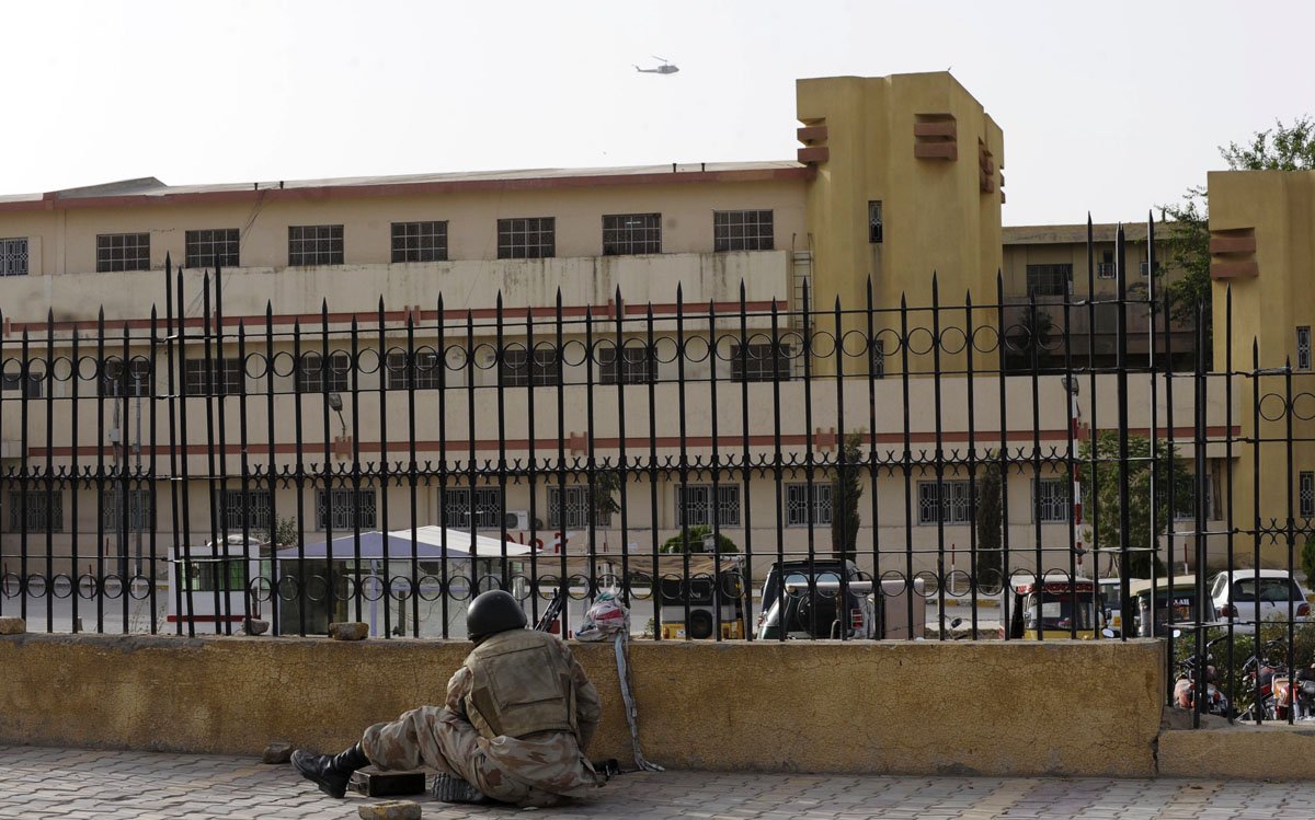 a paramilitary soldier takes up position outside the bolan medical complex as a helicopter circles above photo afp