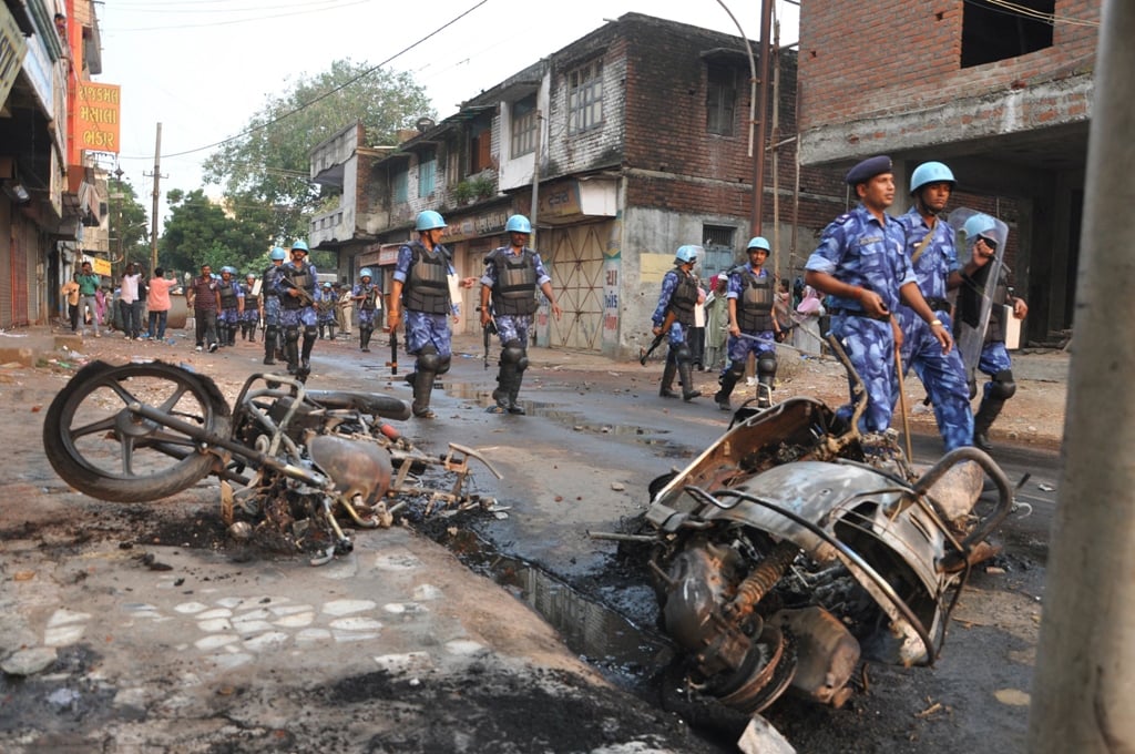 in this photograph taken on september 25 2014 paramilitary soldiers from the rapid action force raf walk past burnt vehicles as they patrol the streets of vadodara city some 110 kms from ahmedabad indian police in prime minister narendra modi 039 s home state of gujarat have arrested more than 200 people after violence between majority hindus and minority muslims a senior officer said september 29 2014 photo afp