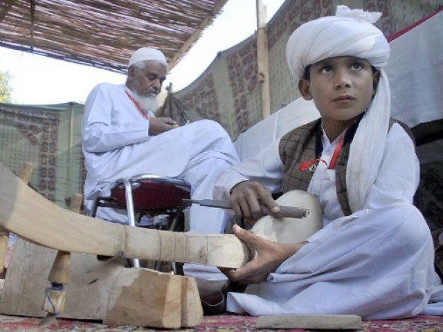 a young boy makes a traditional baloch musical instrument during the 039 artisan at work 039 festival at lok virsa photo online