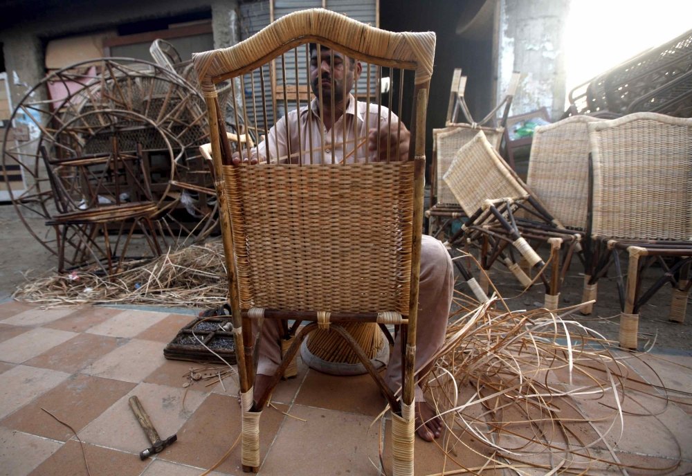 a carpenter weaves strips while making a bamboo chair at a workshop in karachi pakistan photo reuters