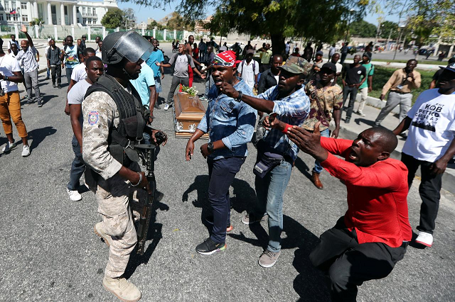 local residents argue with a policeman while the casket of a man shot dead during anti government protests lies on the ground in port au prince haiti february 22 2019 photo reuters