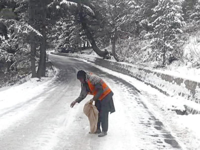a worker spreads salt on a snow covered road to prevent vehicles from slipping on the icy concrete photo express a worker spreads salt on a snow covered road to prevent vehicles from slipping on the icy concrete photo express