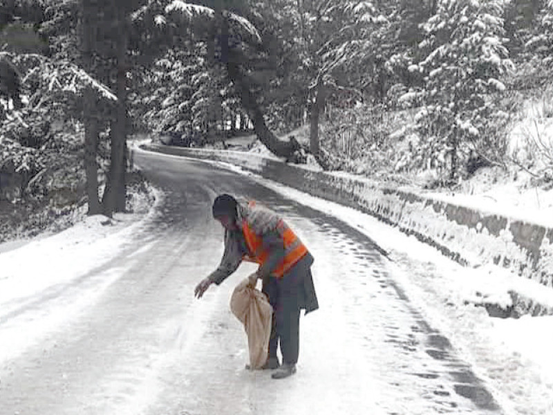 a worker spreads salt on a snow covered road to prevent vehicles from slipping on the icy concrete photo express