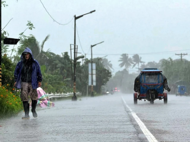 a man walks along a road amid heavy rain due to weather patterns from super typhoon ragasa in lal lo town cagayan province philippines photo afp