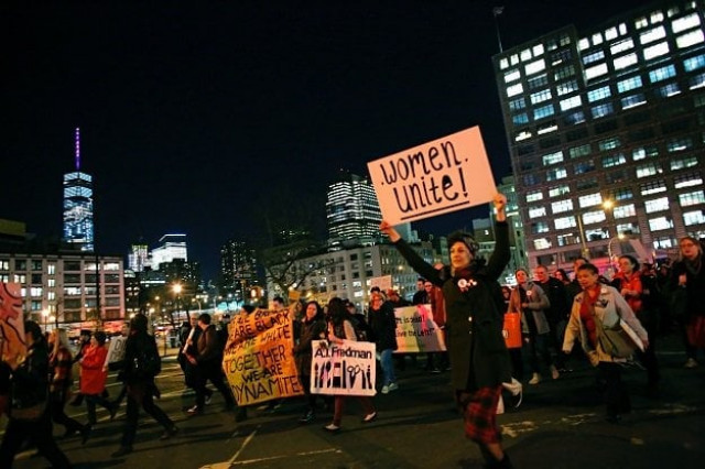 people hold up signs during an international women 039 s strike rally on march 8 2017 in new york city photo afp