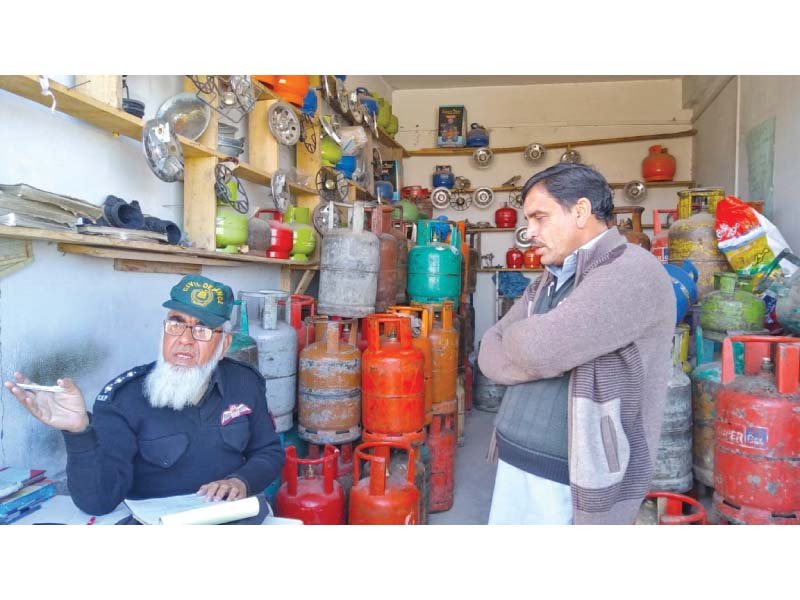 a civil defence official fines a shopkeeper for selling gas cylinders illegally at his shop in rawalpindi photo express