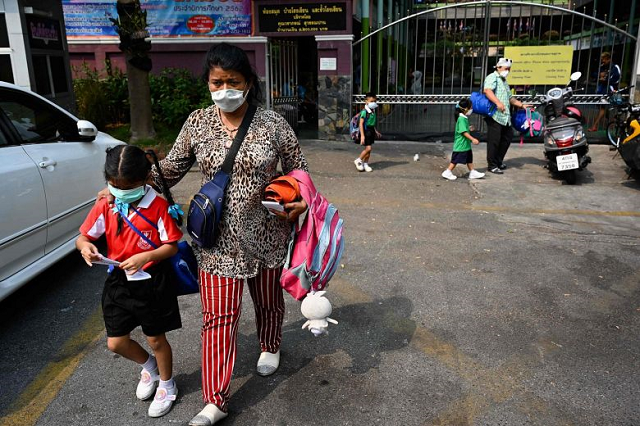 a woman picks up a child from school early due to pollution in bangkok on january 30 2019 photo afp