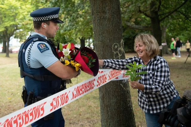 a woman hands flowers to a police officer to the dean avenue mosque in christchurch photo afp a woman hands flowers to a police officer to the dean avenue mosque in christchurch photo afp