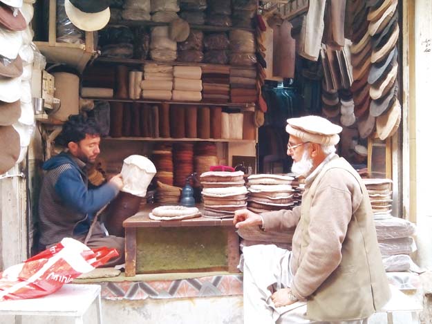 a shopkeeper gives final touches to a pakol photos abdur razzaq