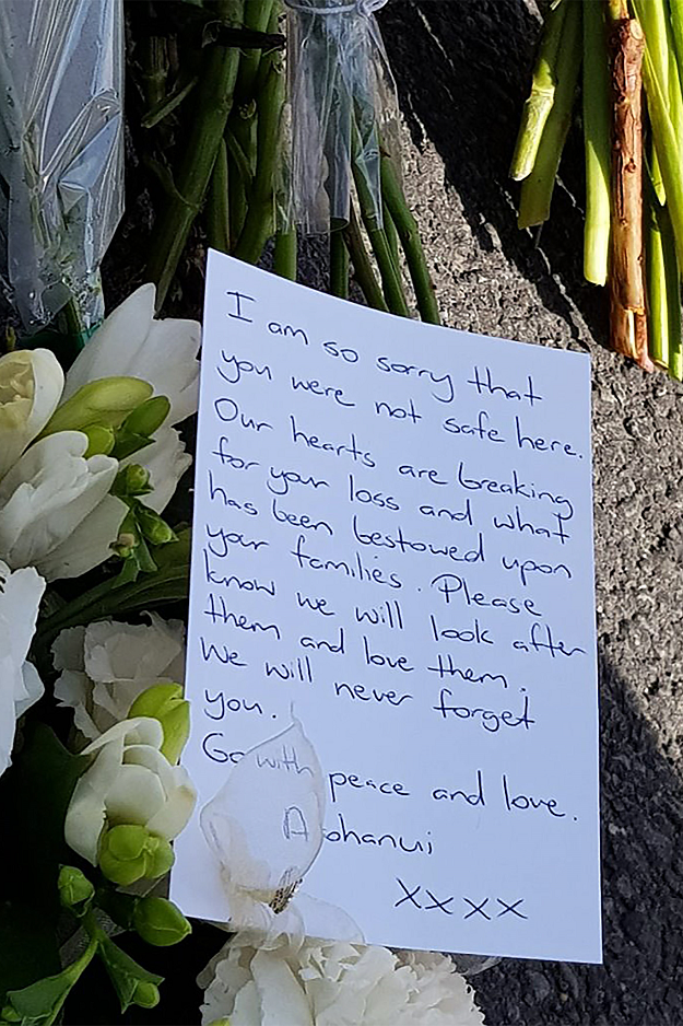 a letter is seen as residents pay their respects by placing flowers for the victims of the mosques attacks in christchurch photo afp