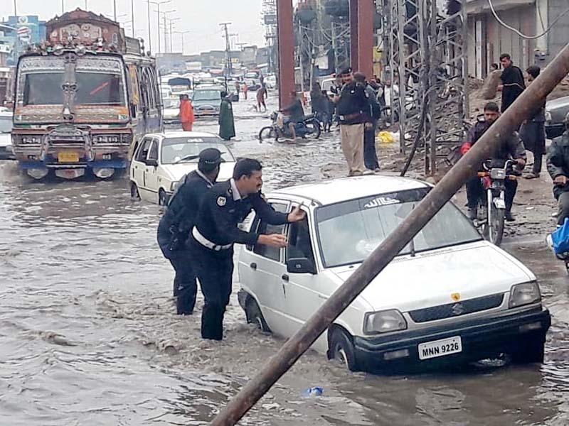 policemen help a motorist on a flooded road in peshawar photo express