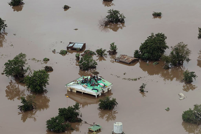 people on a roof surrounded by flooding in an area affected by cyclone idai in beira photo afp
