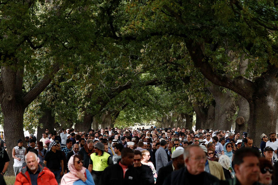 members of the public look on during a gathering for congregational friday prayers and two minutes of silence for victims of the twin mosque massacre at hagley park in christchurch photo afp