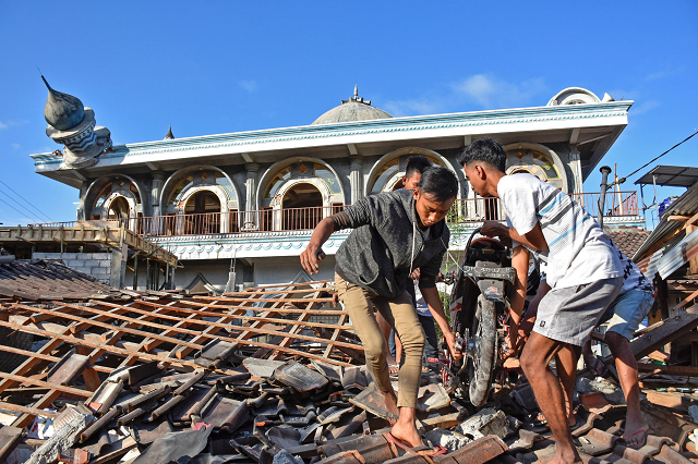 people in western lombok indonesia pulling a motorcycle from a damaged home near a mosque photo reuters