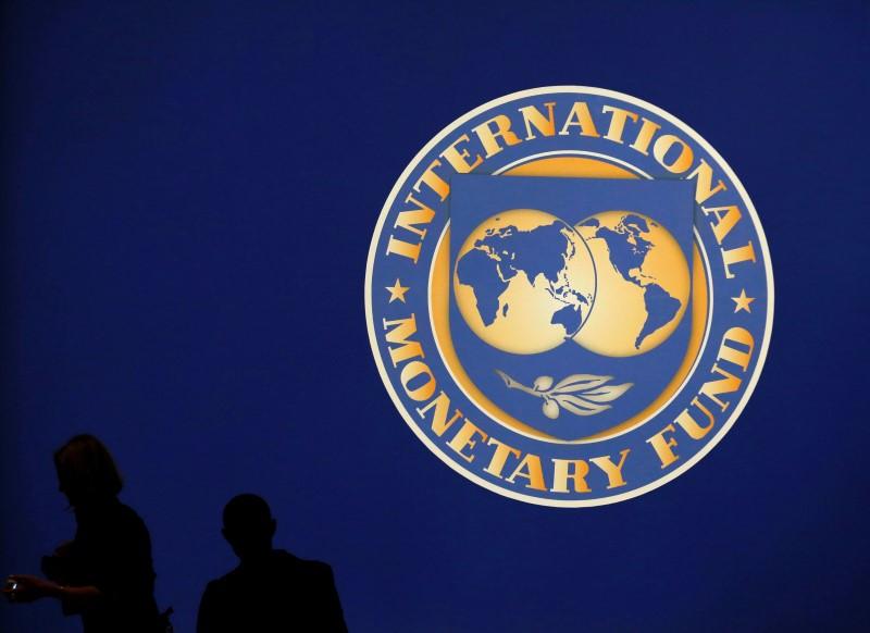 visitors are silhouetted against the logo of the international monetary fund at the main venue for the imf and world bank annual meeting in tokyo photo reuters