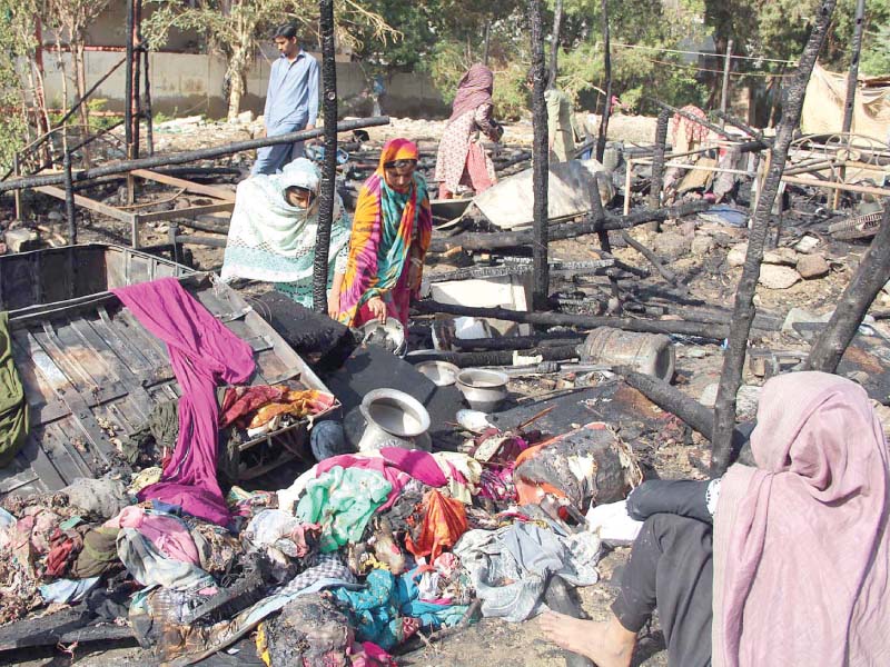 residents of the burnt huts in gulshan e iqbal search for their belongings in the remains photo online