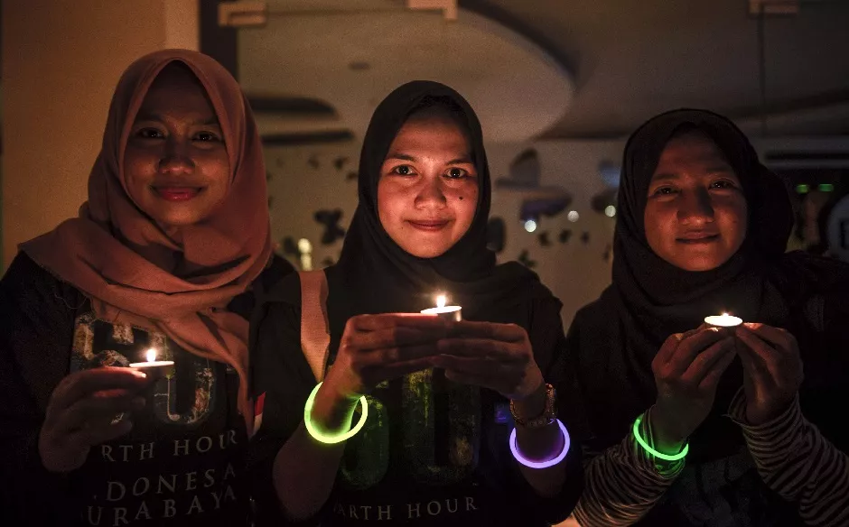 indonesian girls pose for photographs as they hold candles for the earth hour environmental campaign in surabaya east java province on march 30 2019 photo afp indonesian girls pose for photographs as they hold candles for the earth hour environmental campaign in surabaya east java province on march 30 2019 photo afp