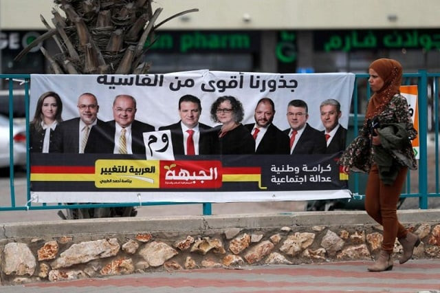 an israeli arab woman walks past a campaign poster showing israeli arab candidates in kfar menda photo afp an israeli arab woman walks past a campaign poster showing israeli arab candidates in kfar menda photo afp