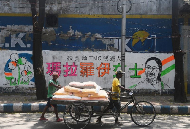 delivery men walk past a mural bearing chinese characters in support of a trinamool congress candidate in kolkata photo afp delivery men walk past a mural bearing chinese characters in support of a trinamool congress candidate in kolkata photo afp