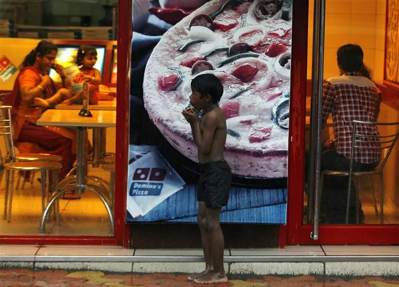 a homeless boy holds biscuits that he received as alms as he takes shelter from rain in front of a fast food shop in mumbai photo reuters a homeless boy holds biscuits that he received as alms as he takes shelter from rain in front of a fast food shop in mumbai photo reuters