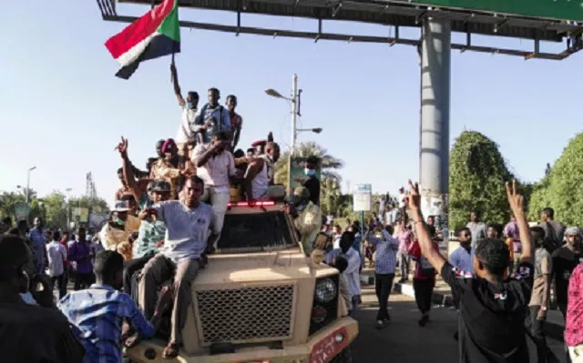 sudanese protesters wave a national flag and flash the victory sign as they sit atop a military vehicle next to soldiers near the capital khartoum 039 s military headquarters on 7 april 2019 photo afp sudanese protesters wave a national flag and flash the victory sign as they sit atop a military vehicle next to soldiers near the capital khartoum 039 s military headquarters on 7 april 2019 photo afp