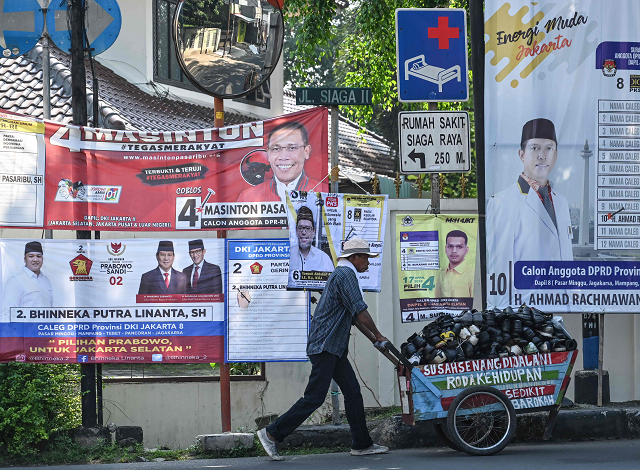 a man pushing a cart past election campaign banners in jakarta photo afp