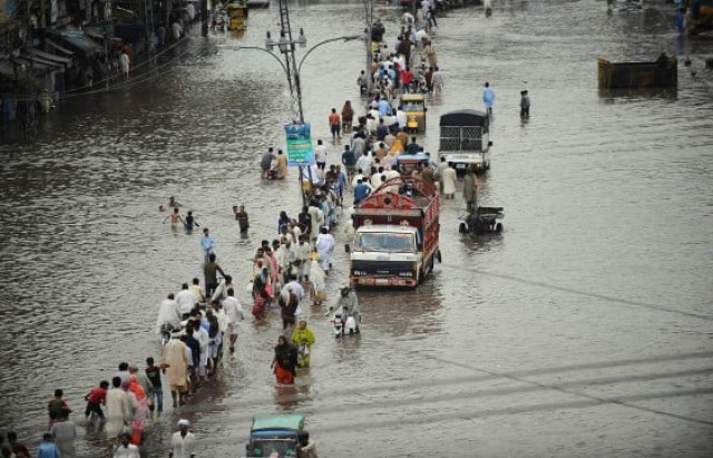 commuters travel through a flooded street in lahore photo afp commuters travel through a flooded street in lahore photo afp