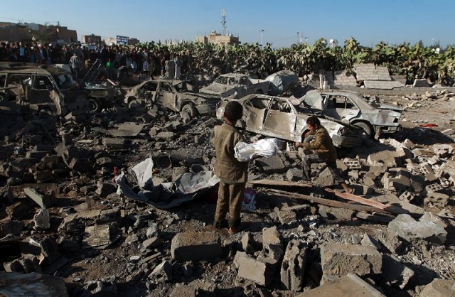 yemeni civilians stand at the site of a saudi air strike against huthi rebels near sanaa airport on march 26 2015 photo afp