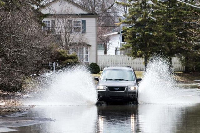 a car crosses a flooded street in laval canada on april 21 2019 as the authorities remain on high alert in expectation of more surges of water across southern quebec photo afp