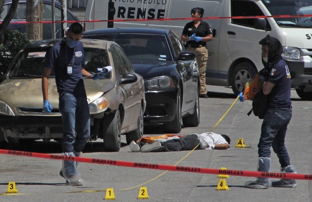 forensic experts and investigators of the prosecution office work at the crime scene next to a man 039 s corpse in ciudad juarez mexico on april 20 2019 photo afp