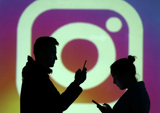 silhouettes of mobile users are seen next to a screen projection of instagram logo in this picture illustration taken march 28 2018 photo reuters