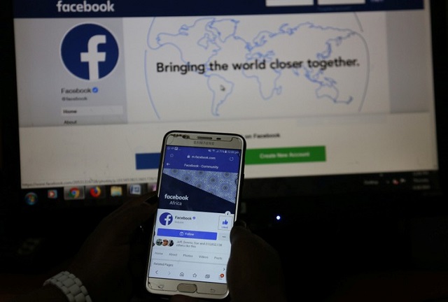 an illustration photo shows the facebook page displayed on a mobile phone internet browser held in front of a computer screen at a cyber cafe in downtown nairobi kenya april 18 2019 photo reuters