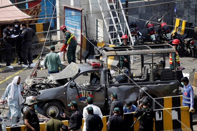 police officers survey while rescue workers attend to a body at the site of a blast in lahore photo reuers