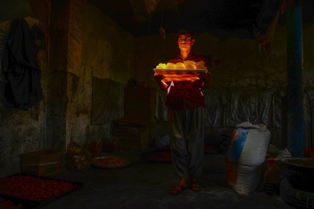 an afghan worker carries sweets at a traditional factory ahead of the start of islamic holy month of ramadan in herat province photo afp