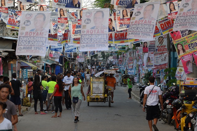 residents walk past posters of candidates for the midterm elections near a polling precinct in manila photo afp