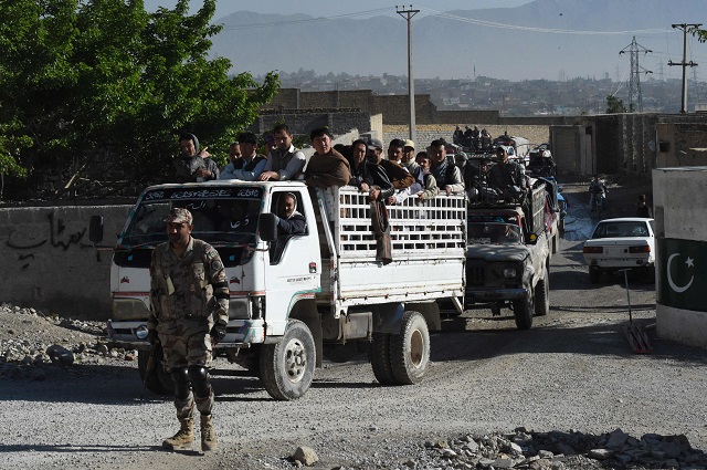 in this picture taken on april 18 2019 a pakistani paramilitary soldier stands guard as vehicles carry hazara minority traders to a fruit and vegetable market from their heavily guarded enclave where they live on the outskirts of quetta photo afp