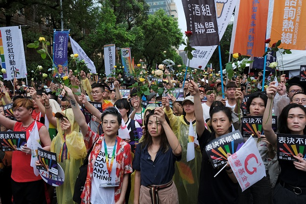 same sex marriage supporters hold roses to mourn those who committed suicide due to discrimination during a parliament vote on three draft bills of a same sex marriage law outside the legislative yuan in taipei photo reuters