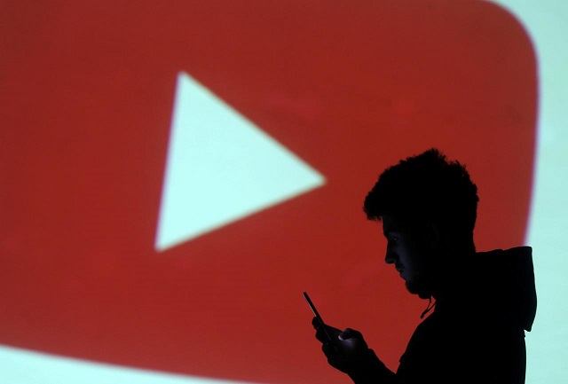 silhouette of mobile user is seen next to a screen projection of youtube logo in this picture illustration taken march 28 2018 photo reuters