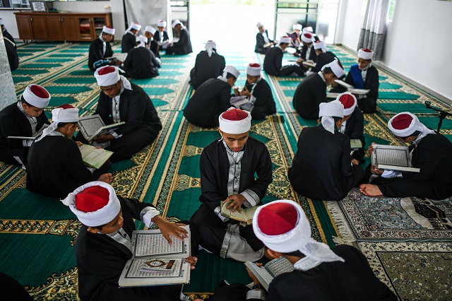 this picture shows muslim students reading copies of the holy qoran to observe nuzul quran when the beginnings of the quran were revealed to the prophet mohammed pbuh in a mosque in bentong photo afp