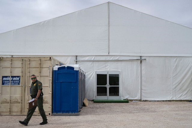 a us border patrol agent walks by a new temporary holding facility opened by customs and border protection personnel on the us mexico border in el paso texas photo afp