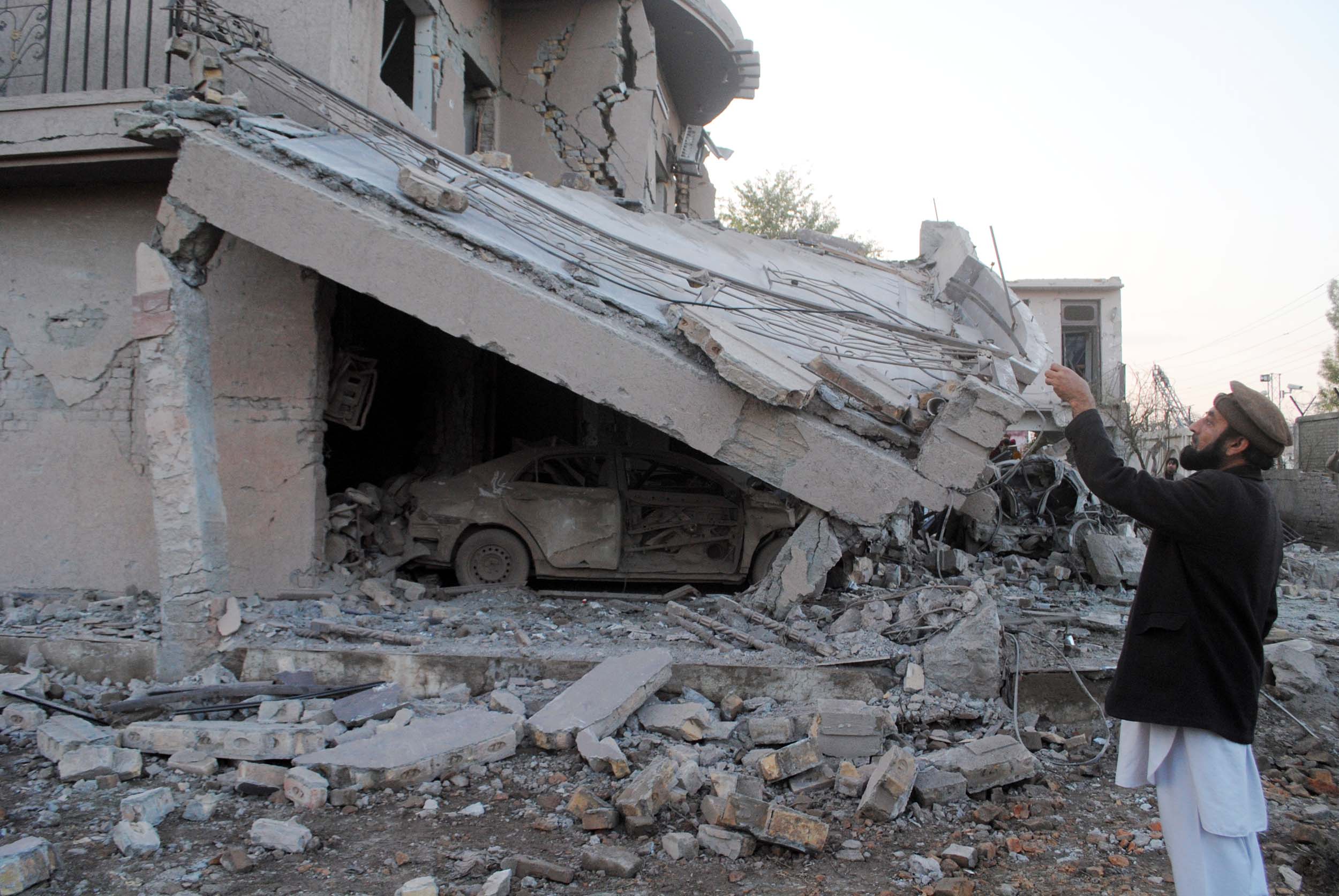 a person takes a photograph of one of the houses destroyed in the aftermath of terrorist attack on the bacha khan international airport in peshawar photo mohammad iqbal express file