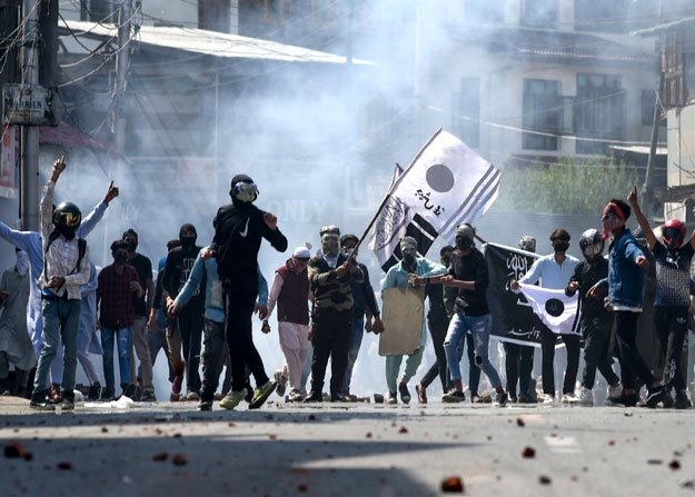 protesters gesture towards indian police personnel through teargas smoke during a clash in occupied kashmir s srinagar on may 31 2019 photo afp