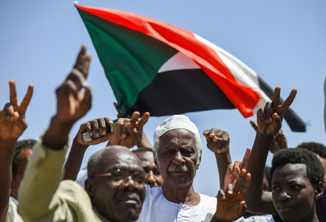 sudanese protesters chant slogans flash v for victory signs and wave the national flag at the sit in outside the army headquarters in the capital khartoum on may 14 2019 photo afp