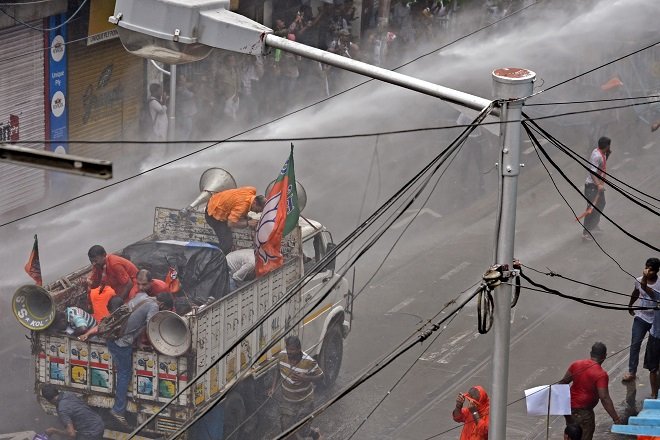 bjp activists shelter on the back of a truck as police use a water canon to disperse demonstrators photo afp