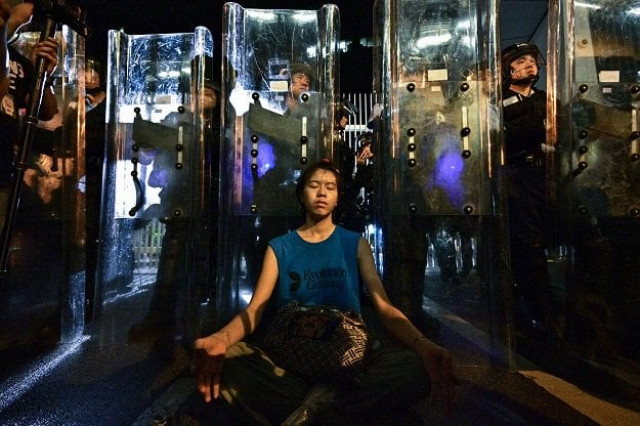 a woman meditates in front of a line of riot police standing guard with their shields outside the government headquarters in hong kong early on june 12 2019 photo afp a woman meditates in front of a line of riot police standing guard with their shields outside the government headquarters in hong kong early on june 12 2019 photo afp