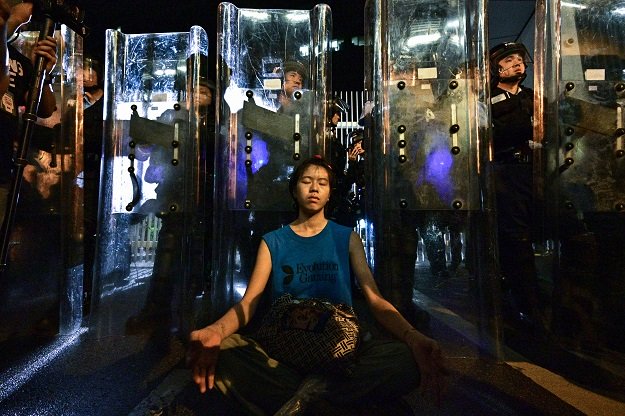 a woman meditates in front of a line of riot police standing guard with their shields outside the government headquarters in hong kong early on june 12 2019 photo afp